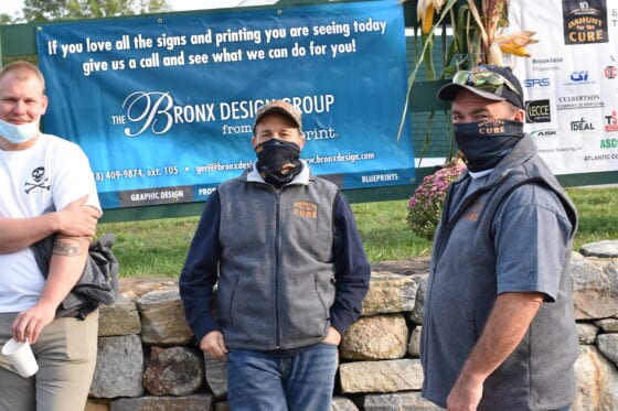 Three masked men standing in front of banner