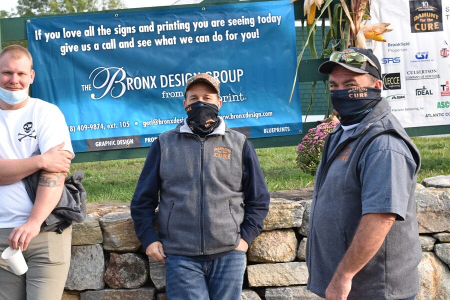 Three masked men standing in front of banner