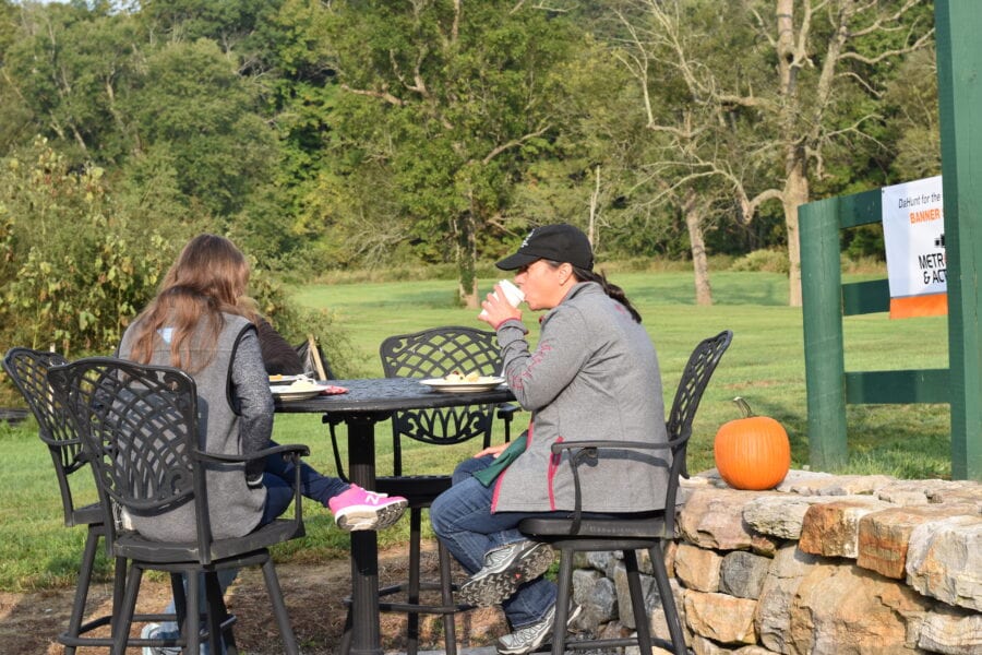 Two people seated at outdoor table with pumpkin