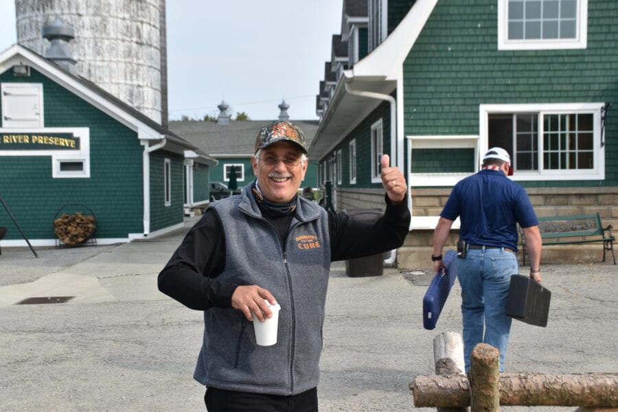 Smiling man giving thumbs up holding coffee