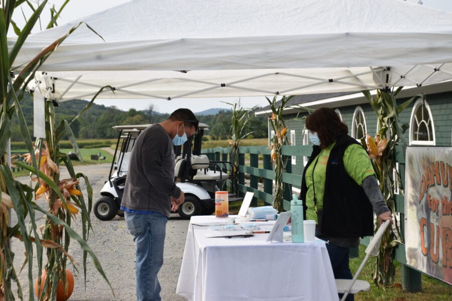 Masked people at outdoor farm check-in