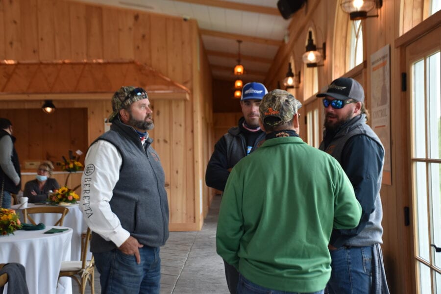Four men talking inside rustic wooden event hall