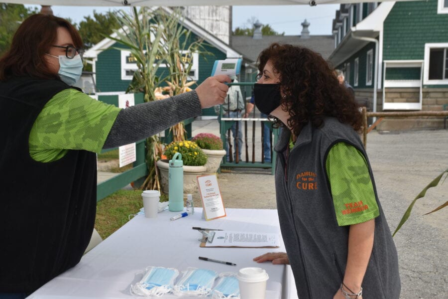 Masked woman having temperature checked at table