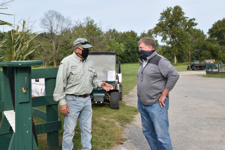 Two masked men talking near golf cart