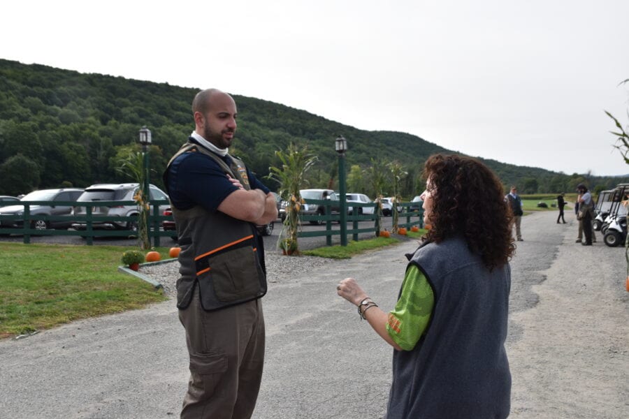 Two people talking near parked cars and hills