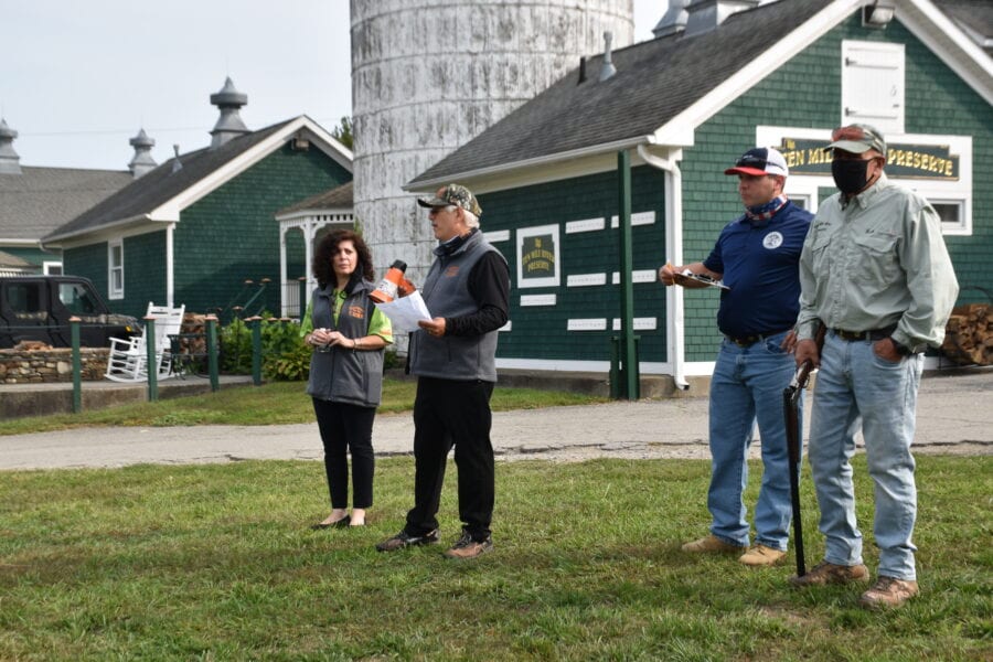 Four people standing near green barn and silo
