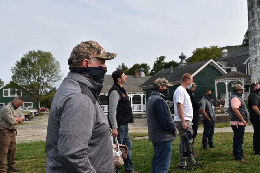 Group of masked people standing outdoors near houses