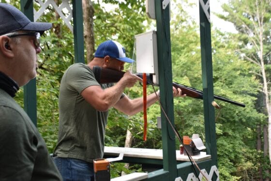 Man aiming shotgun at outdoor shooting range