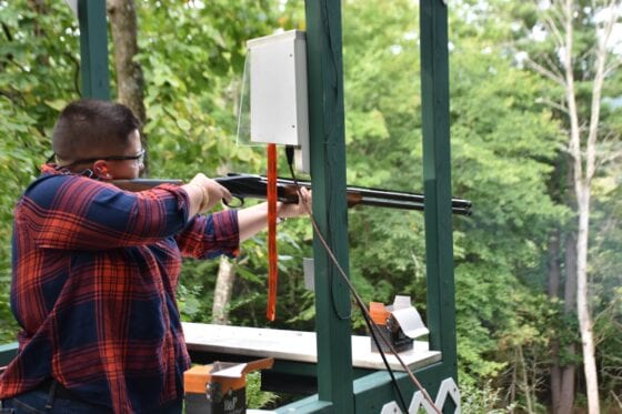 Person aiming shotgun at outdoor shooting range