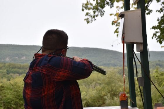 Person firing shotgun at scenic outdoor range