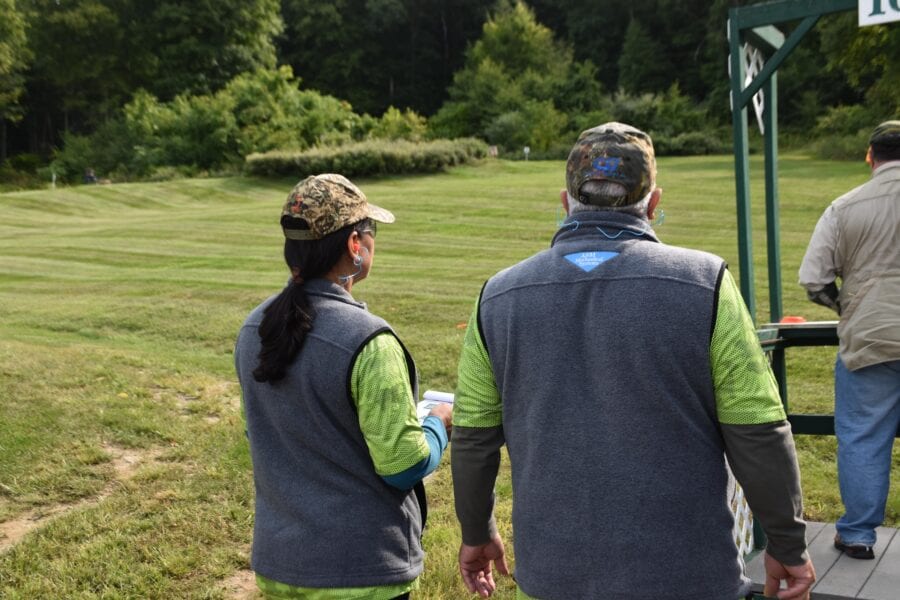 Two people in camo caps walking on grass