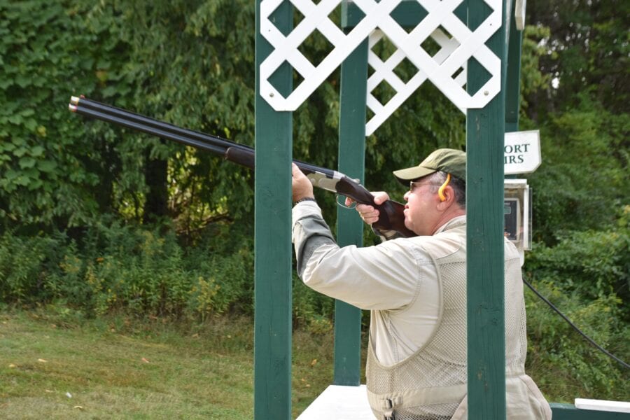 Man firing shotgun at outdoor shooting range
