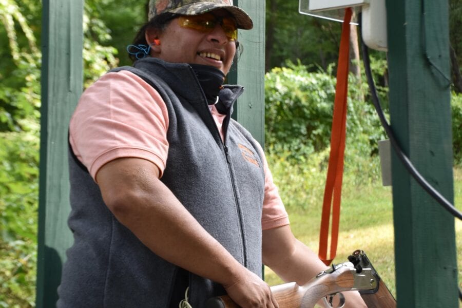 Smiling person holding shotgun at shooting stand