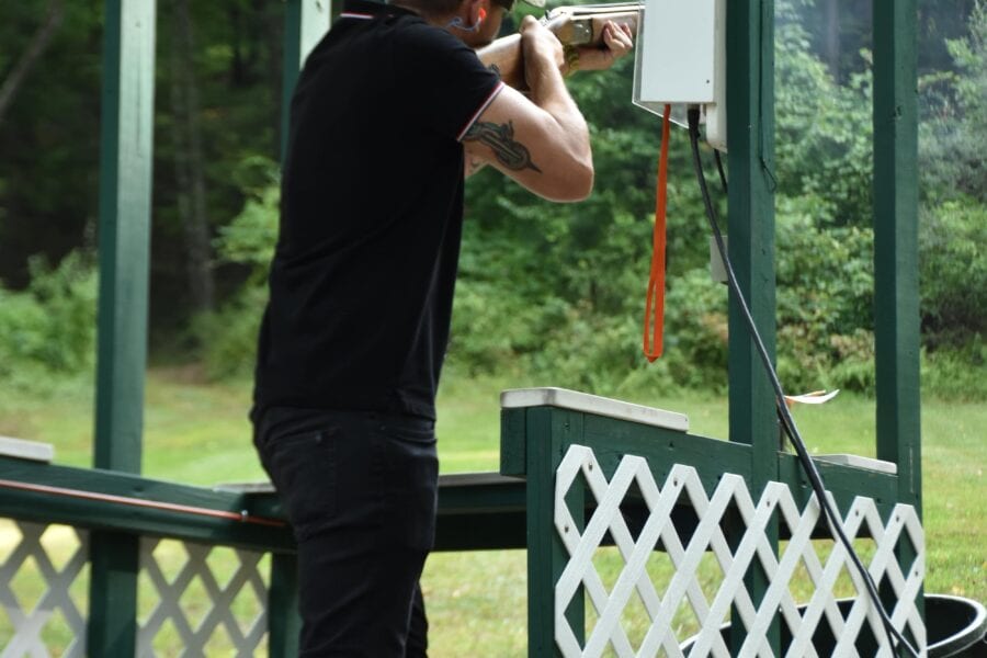 Person firing shotgun at outdoor shooting range