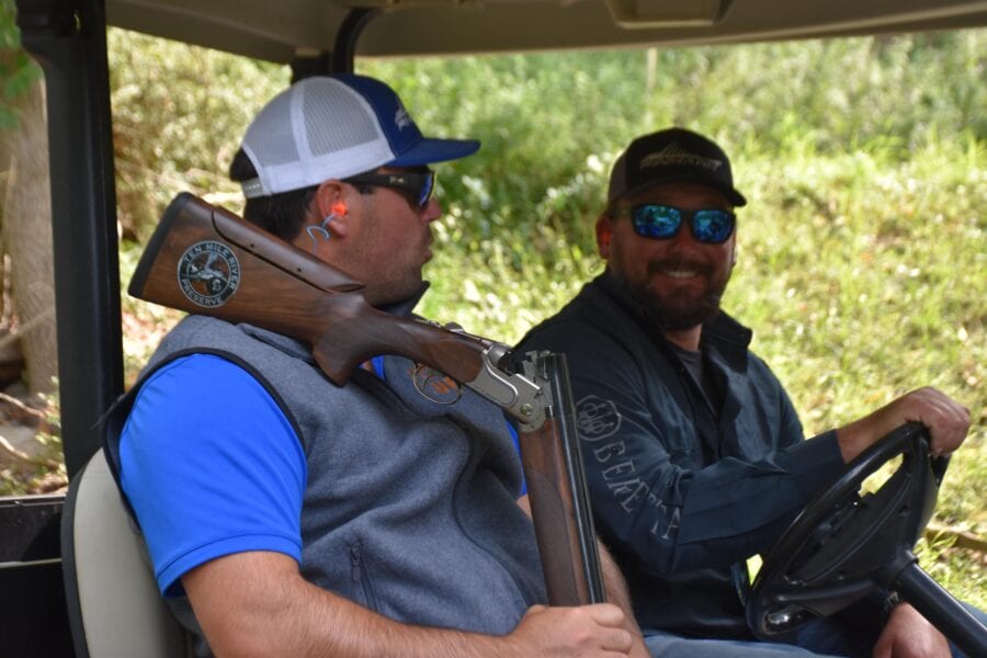 Two men in golf cart with shotgun
