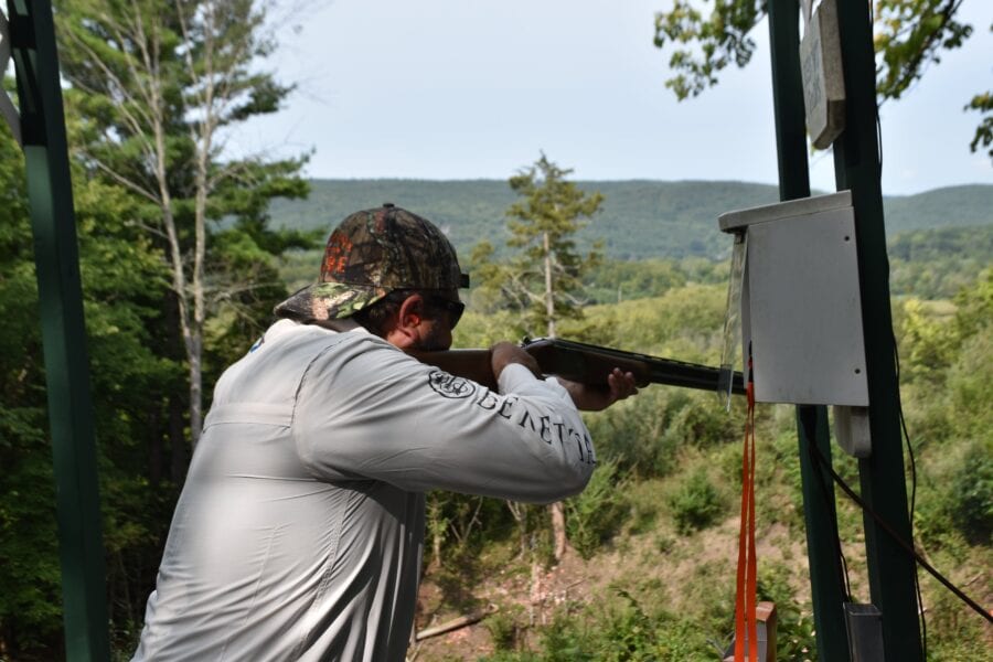 Person aiming shotgun at outdoor shooting range