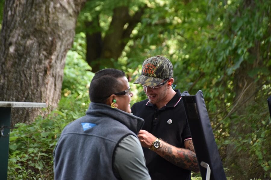 Two men outdoors talking, one carrying a case