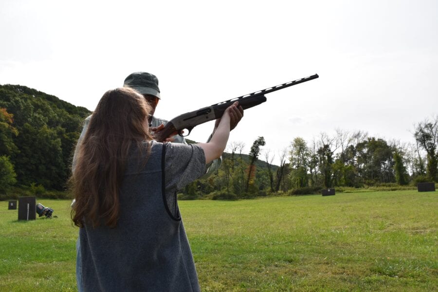 Person receiving shotgun shooting instruction outdoors