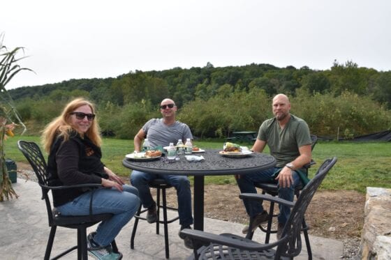 Three people dining outdoors at round patio table
