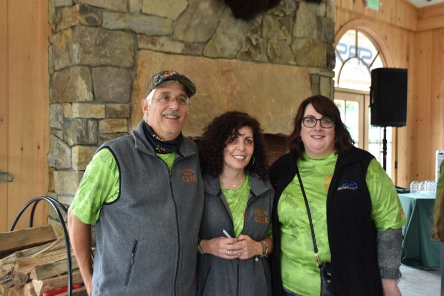 Three smiling volunteers wearing green shirts