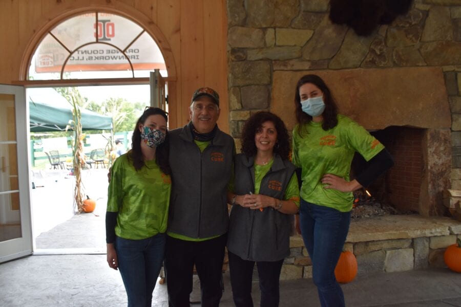 Four people in green shirts by fireplace