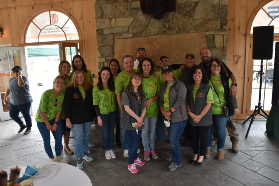 Smiling group in green shirts by stone fireplace
