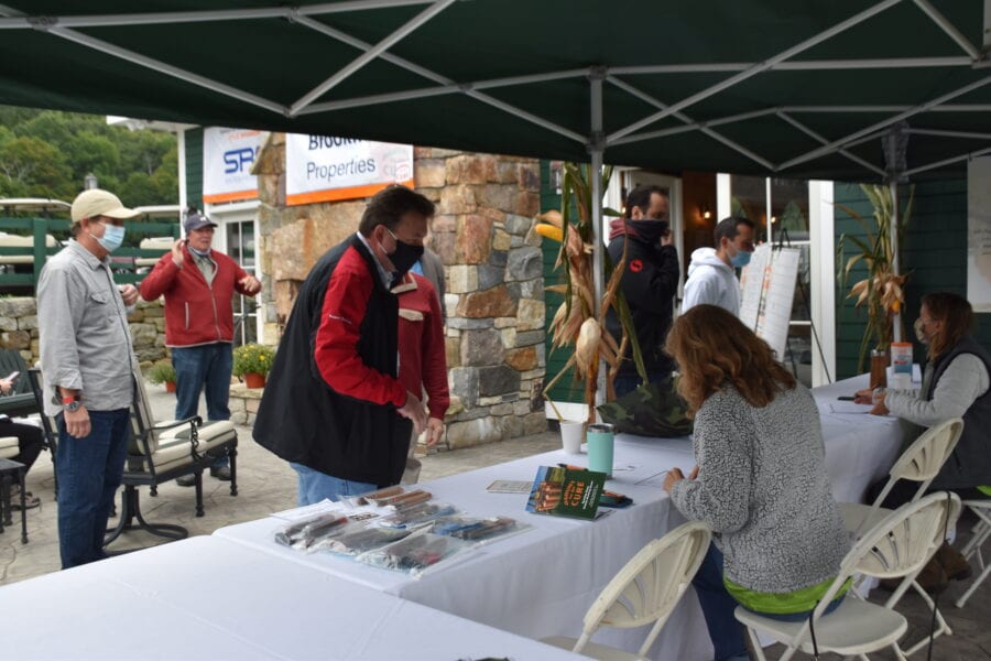 Outdoor registration table under canopy with masked attendees