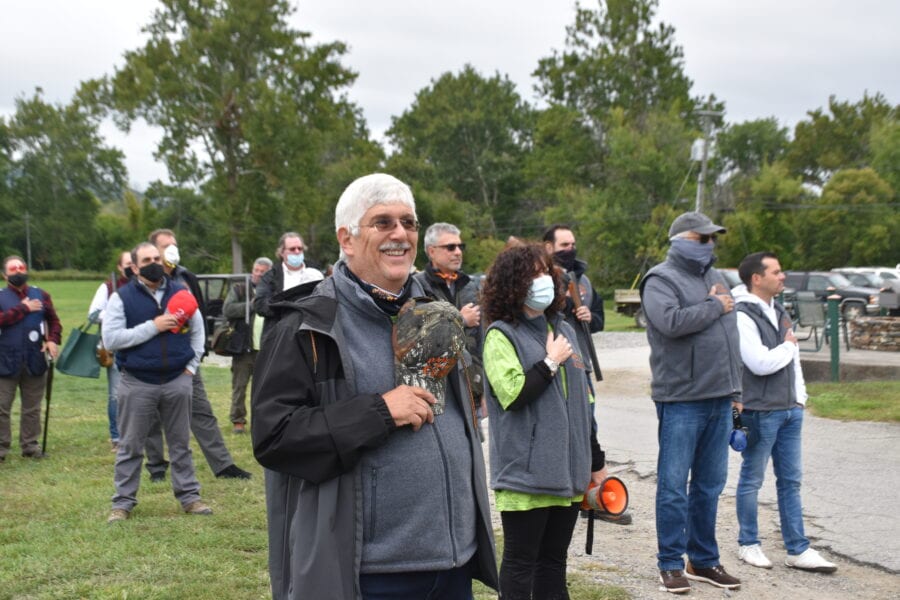 Smiling man holds wreath at outdoor ceremony