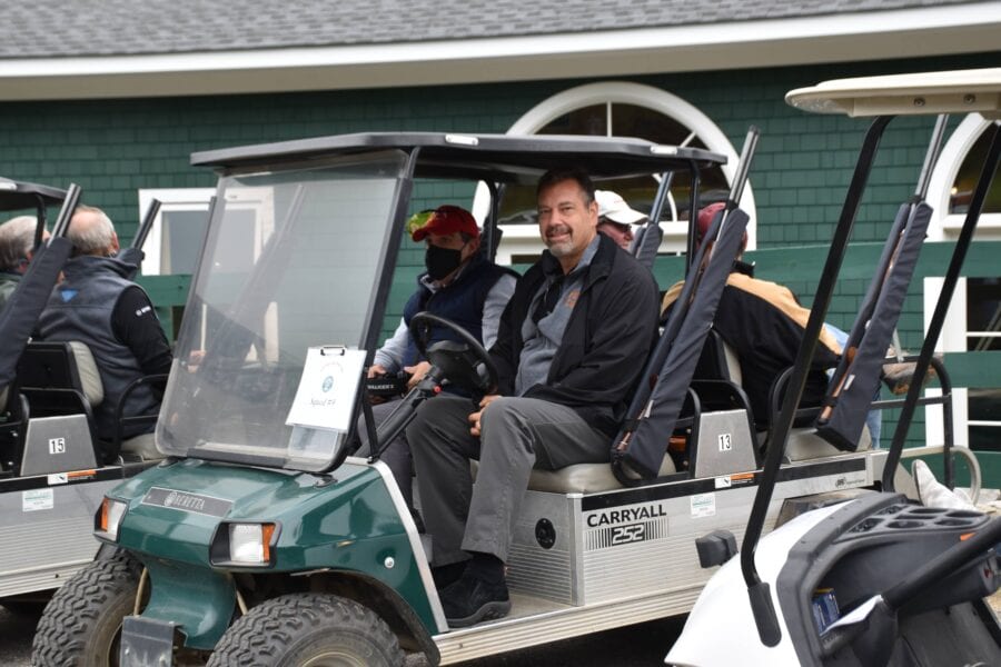 Golfers seated in cart near clubhouse