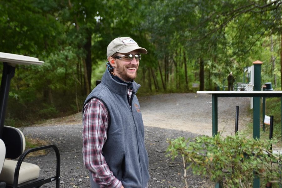 Smiling person in vest by golf cart