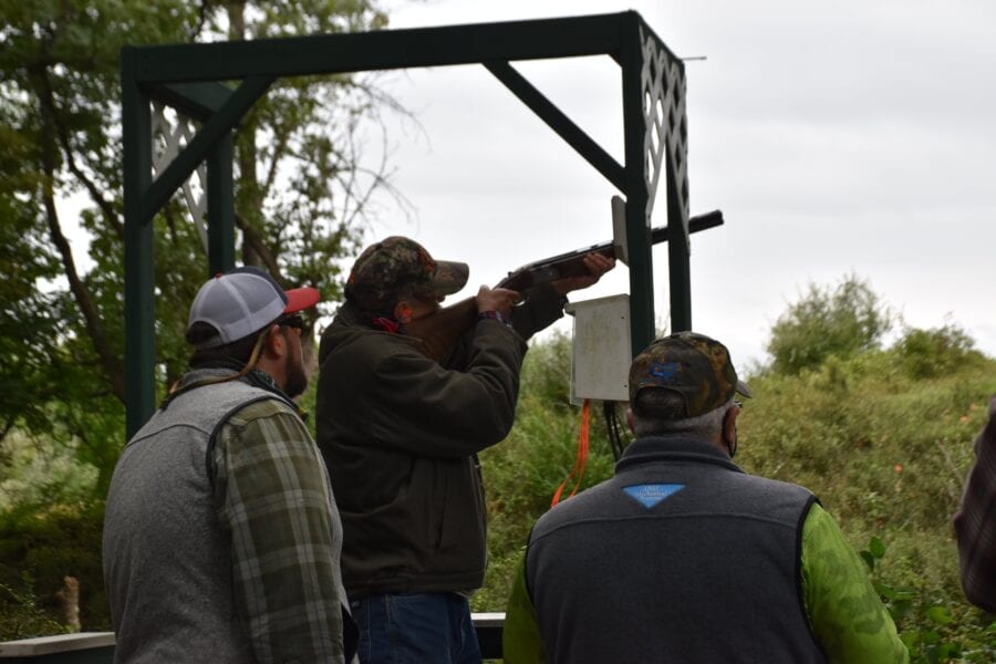 Three men at outdoor clay pigeon shooting range