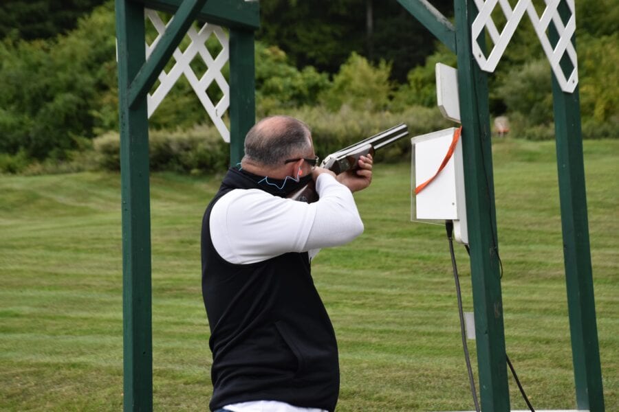 Man aiming shotgun at outdoor clay target