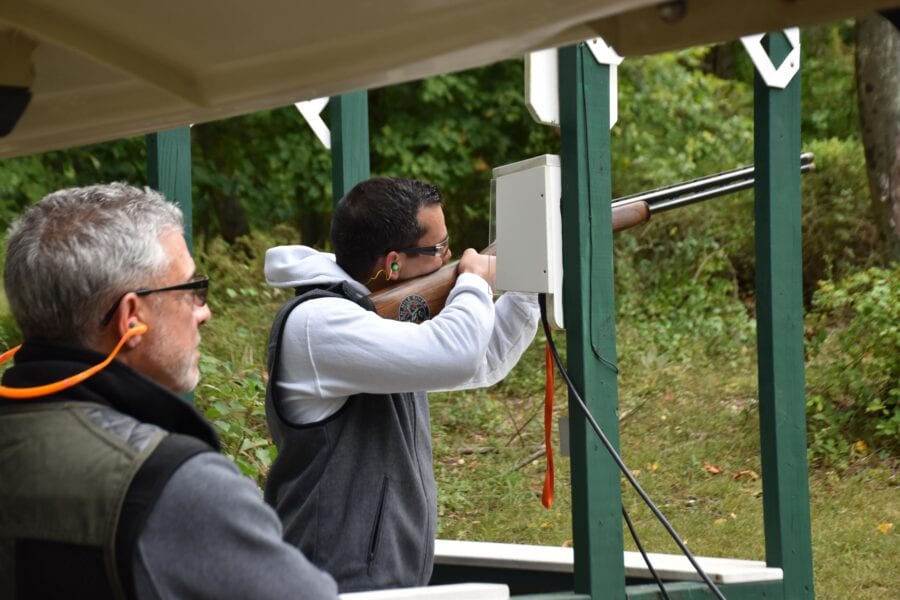 Man aiming shotgun at outdoor shooting range
