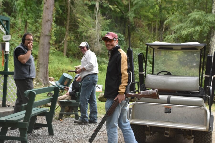 Men with shotgun by golf cart in forest