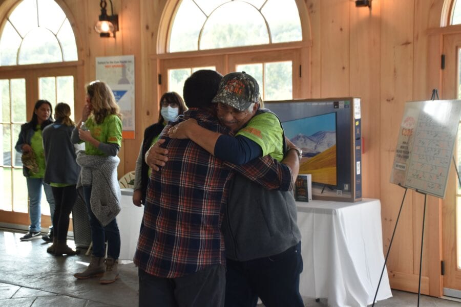 People hugging at indoor community event