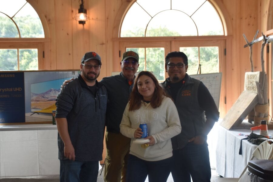 Four people posing in a wooden event room