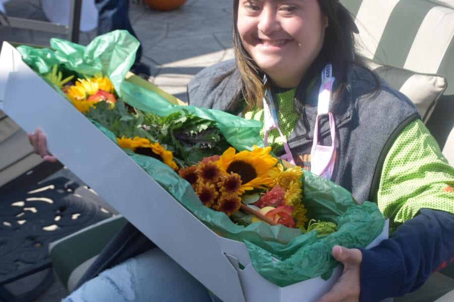 Smiling woman holding box of sunflowers