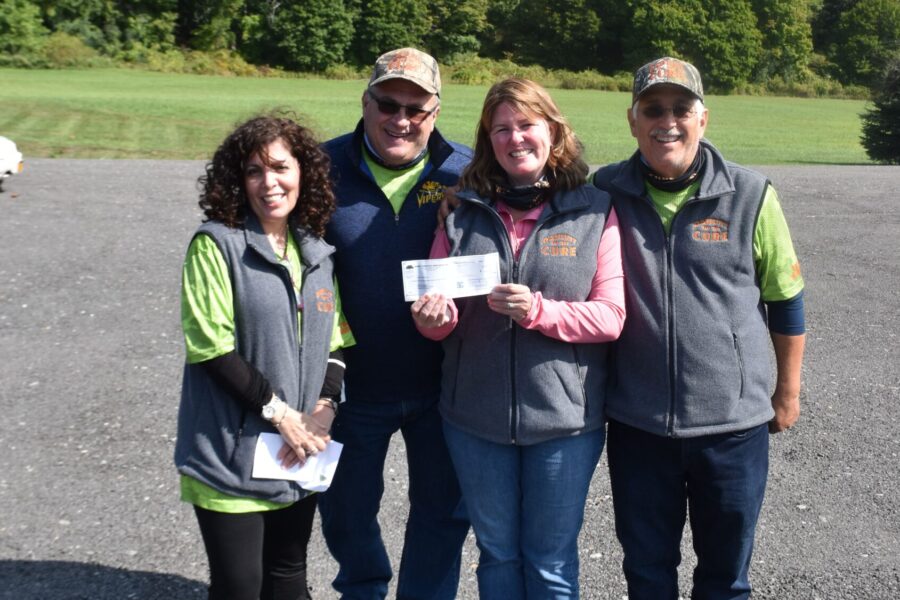 Group of four smiling people holding check