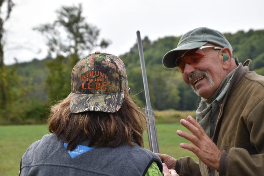 Man instructing shooter holding shotgun outdoors