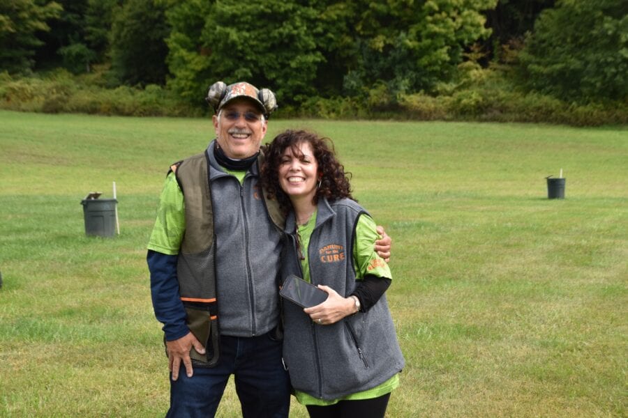 Two people smiling on grassy field wearing vests