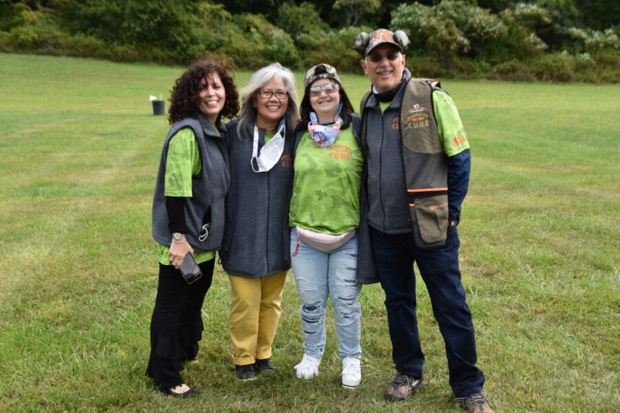 Four smiling people posing on grass
