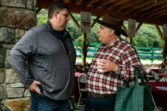 Two men conversing under pavilion, man wearing hat