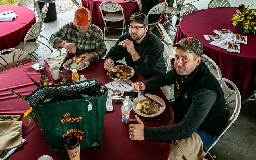 Three men eating meals at round banquet table