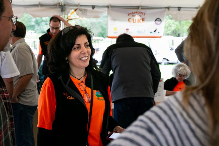 Smiling volunteer in orange shirt at fundraising event