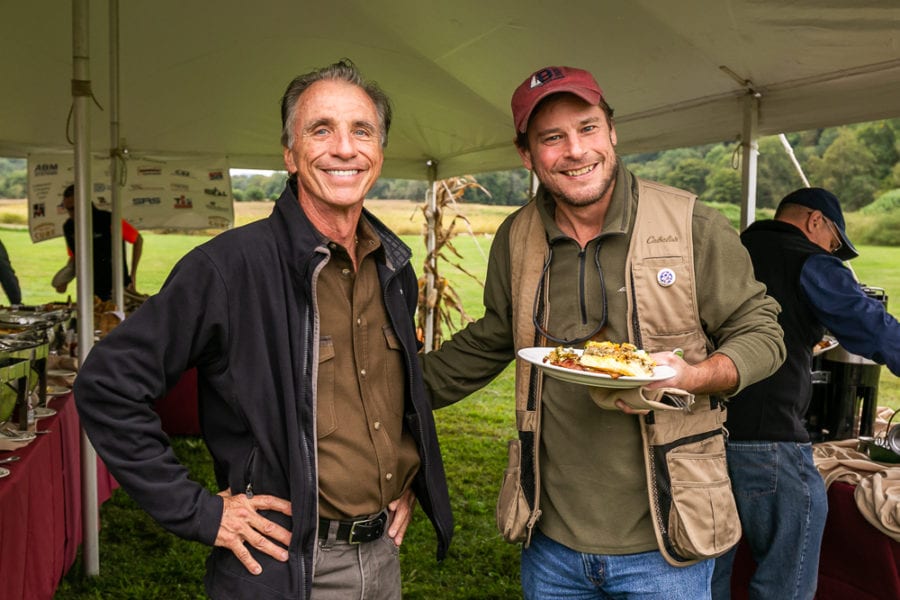 Two men smiling at outdoor buffet tent