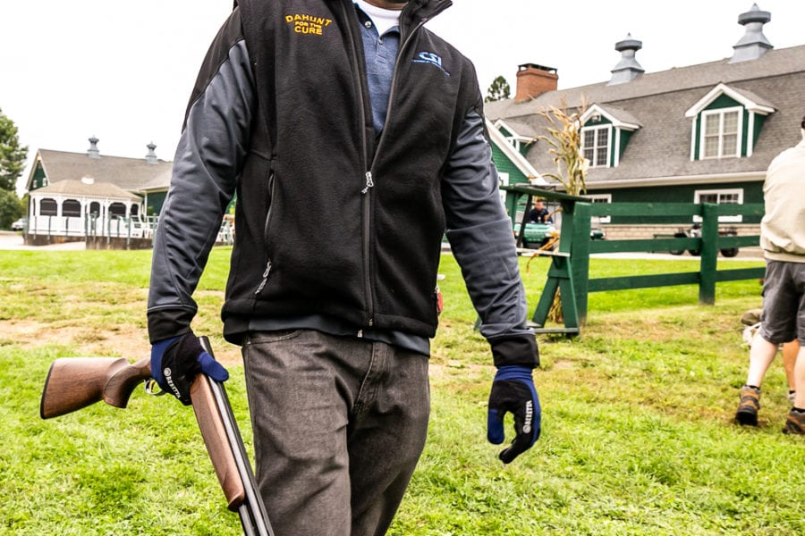 Person walking with shotgun near stables