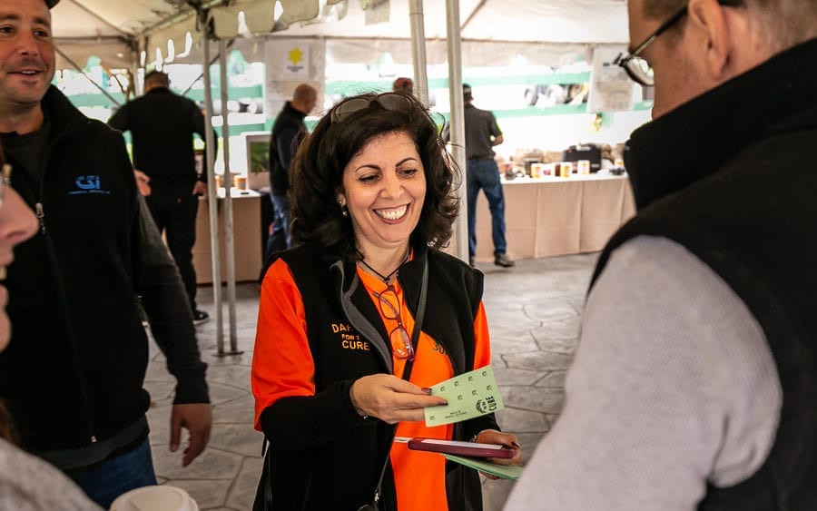 Smiling woman hands raffle tickets at outdoor event