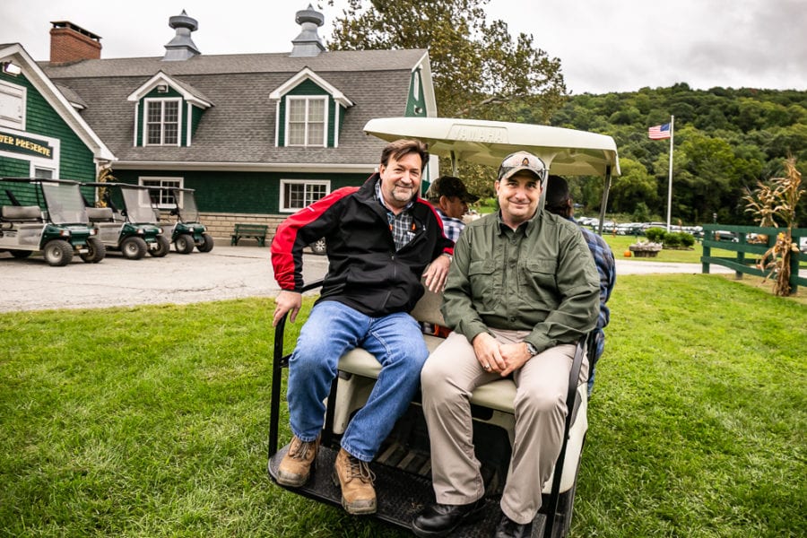 Two men seated on golf cart near lodge