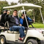 Two men in white golf cart on grass