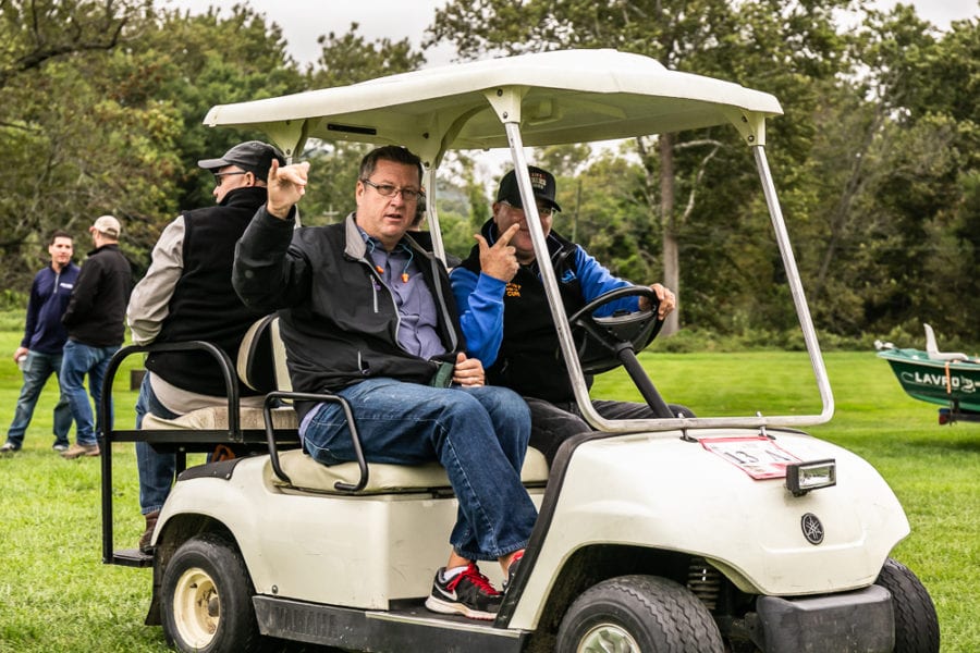 Two men in white golf cart on grass